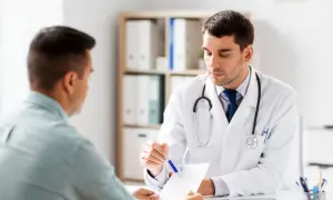 Lekarz w białym kitlu omawia z pacjentem dokumenty. Ważne jest skierowanie do dermatologa, by zadbać o zdrowie skóry.