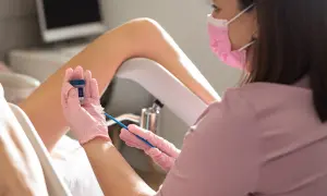 Lekarka w różowej masce i rękawiczkach przygotowuje się do pobrania wymazu. Czy cytologia boli? To badanie jest zazwyczaj bezbolesne.