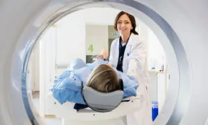 Lekarka uśmiecha się do pacjentki leżącej na stole do rezonansu. Skierowanie na rezonans jest ważne dla diagnostyki.