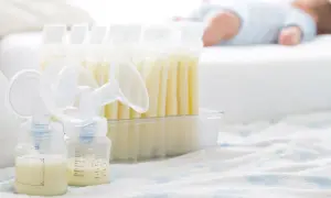 Mleko matki ile może stac w temperaturze pokojowej? Na zdjęciu widać butelki z mlekiem, laktator i śpiące dziecko.
