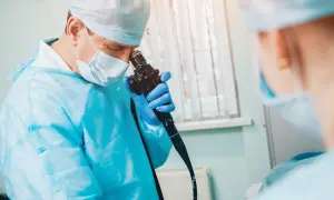 Lekarz w masce i fartuchu przygotowuje się do gastroskopii w Warszawie. NFZ gdzie najlepiej? Sprawdź ofertę.