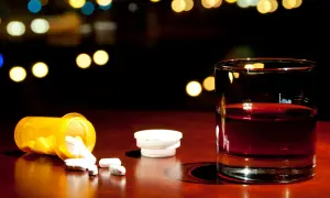 Szklanka z bursztynowym płynem i rozsypane tabletki. Czy rutinoscorbin zawiera paracetamol? To pytanie, które może pojawić się w takiej sytuacji.