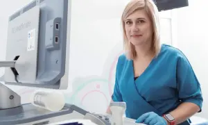 Lekarka w niebieskim fartuchu przy aparacie USG. Czy ginekolog jest na NFZ? Zapytaj w swojej przychodni.