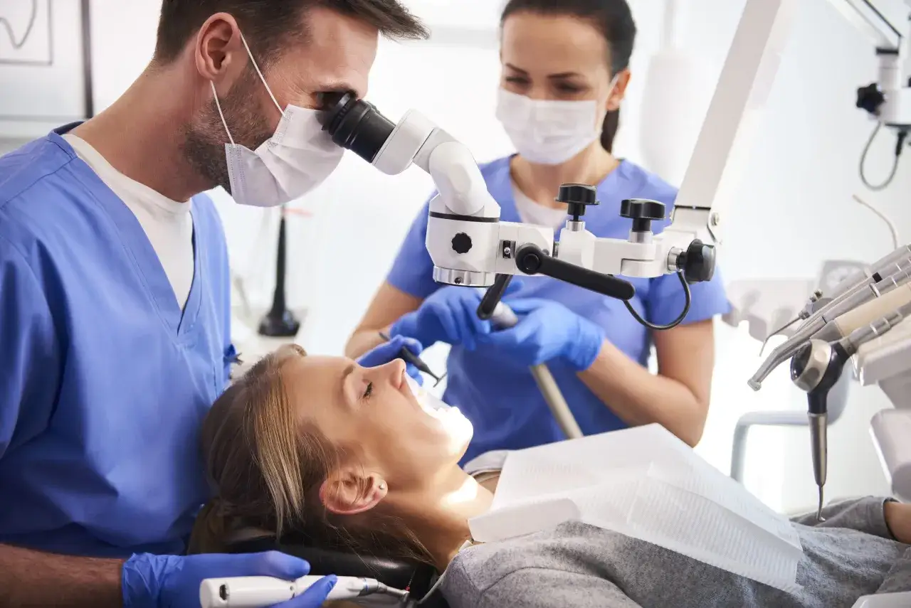 Dentysta w Warszawie wykonuje chirurgiczne usuwanie ósemek pod mikroskopem. Pacjentka w gabinecie stomatologicznym.