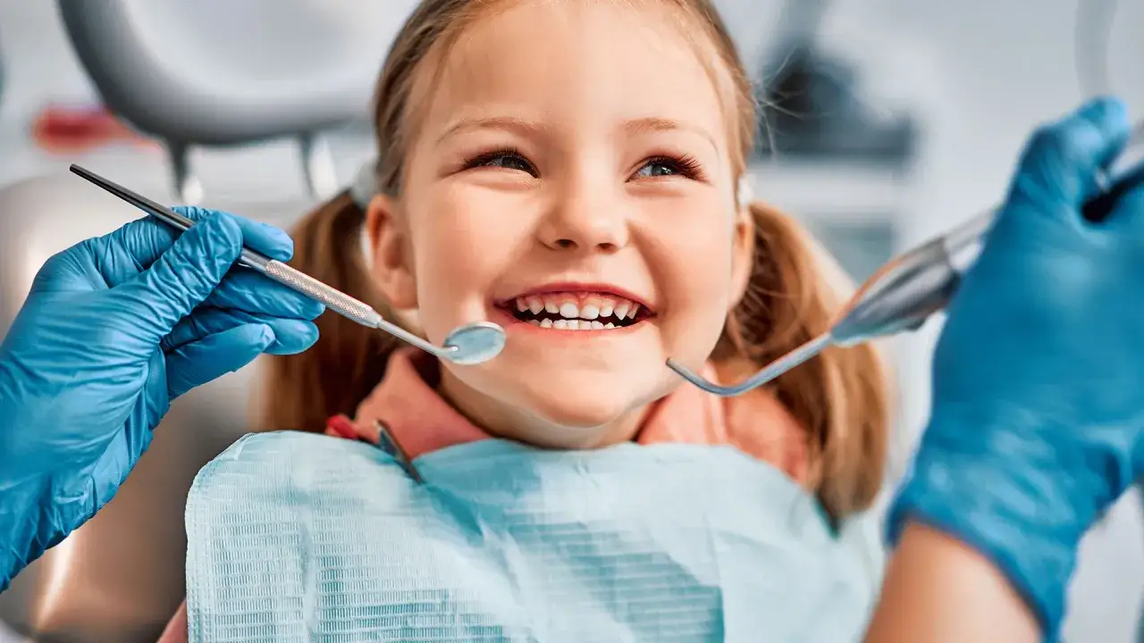 Uśmiechnięta dziewczynka na wizycie u dentysty. Stomatologia dziecięca NFZ to troska o zdrowe zęby od najmłodszych lat.