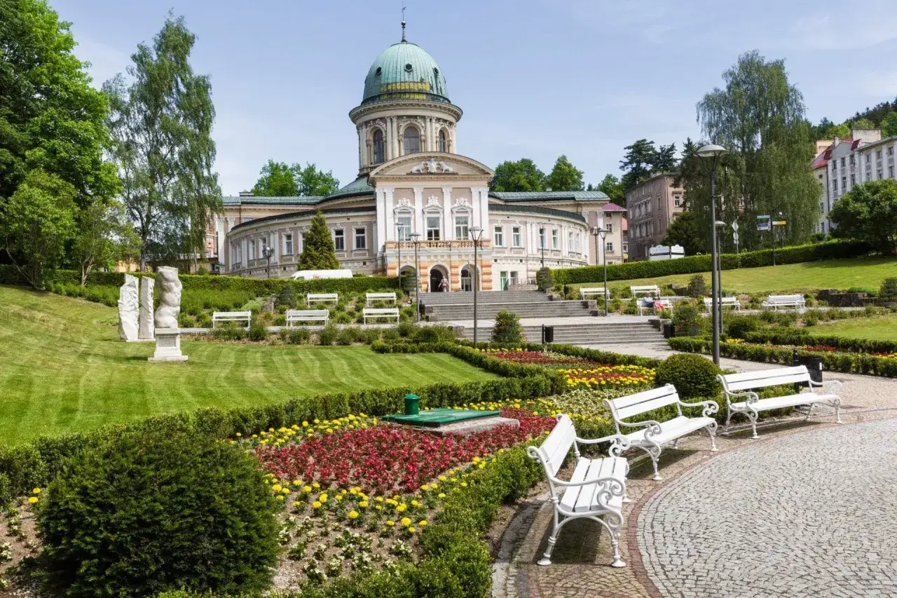 Piękny park z rzeźbami i klombami kwiatów przed sanatorium. Zastanawiasz się, ile kosztuje sanatorium z NFZ?