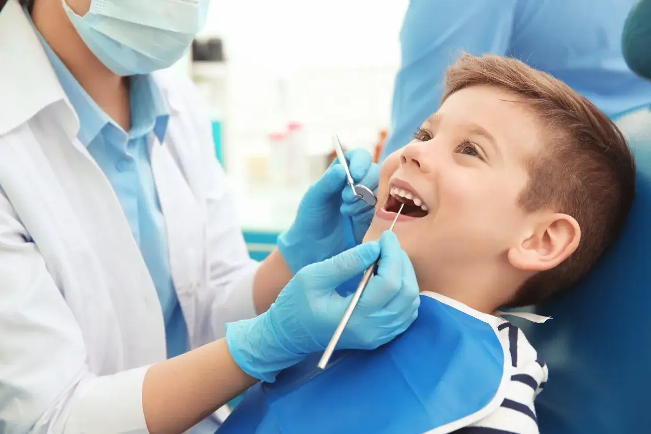 Uśmiechnięty chłopiec u dentysty. Nowy zjazd stomatologia NFZ to szansa na zdrowe zęby dla każdego dziecka.