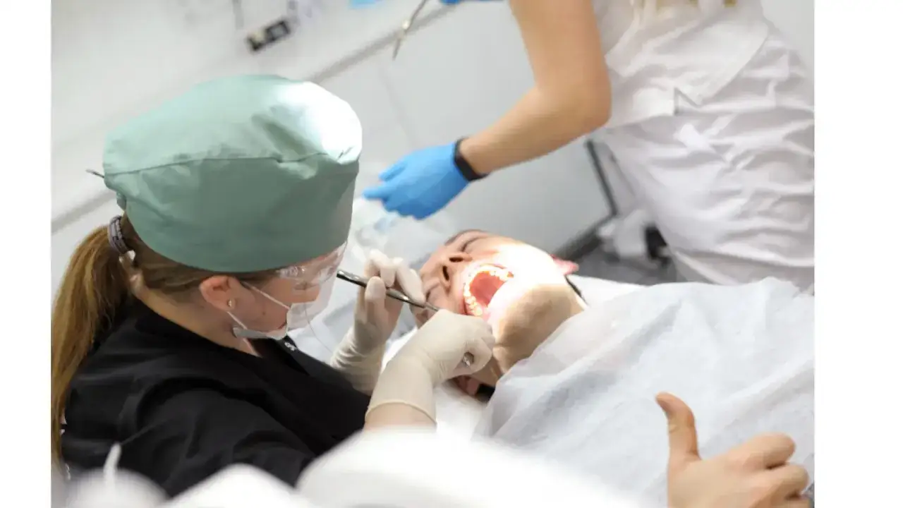 Chirurgiczne usuwanie ósemek NFZ Warszawa. Dentysta w masce i czepku wykonuje zabieg u pacjenta.