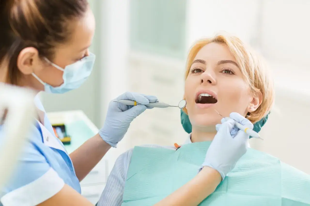 Ostry dyżur stomatologiczny Warszawa NFZ Lindleya: dentystka bada zęby pacjentki.